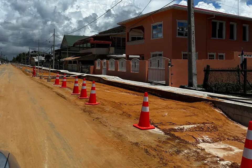 Traffic cones lining a roadway under construction beside a finished building