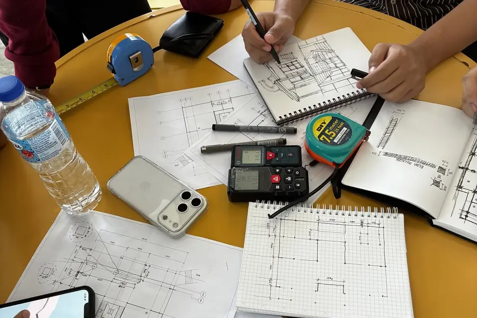 Quantities being taken off a set of drawings with tape measures, laser distance meters, and a gridded notebook