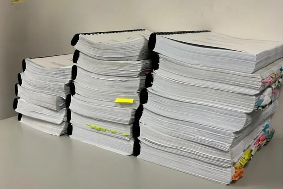 Bound and tabbed volumes of a completed tender submission stacked on a desk